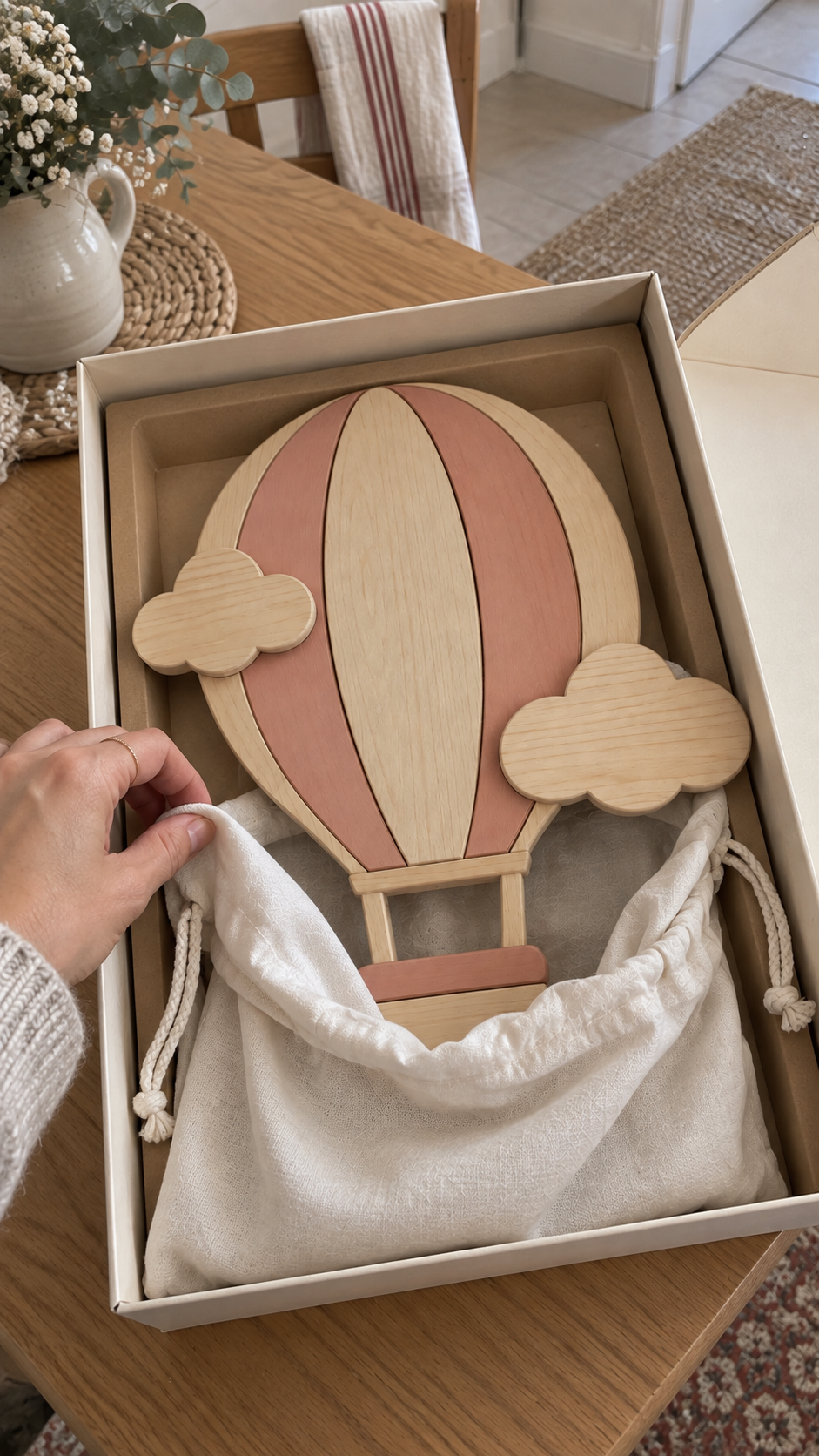 ORAWOOD Montgolfière Nuages roses — déballage illustratif coton blanc 2026-09-29 2/4 — Pochon entrouvert, lampe rose partiellement visible, concept d’emballage illustratif